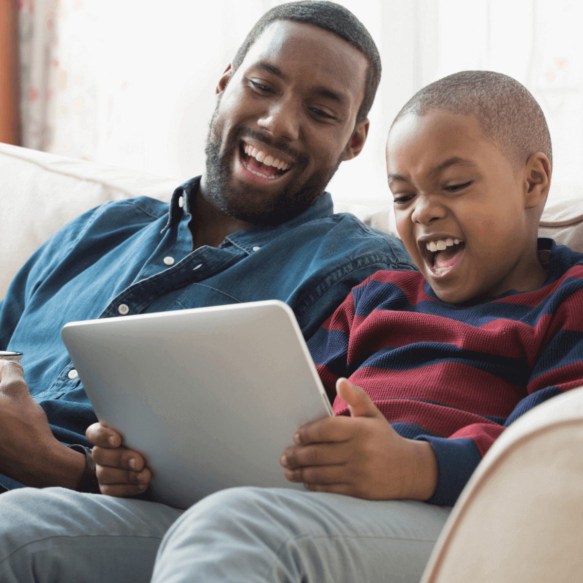 father and son laughing at tablet screen