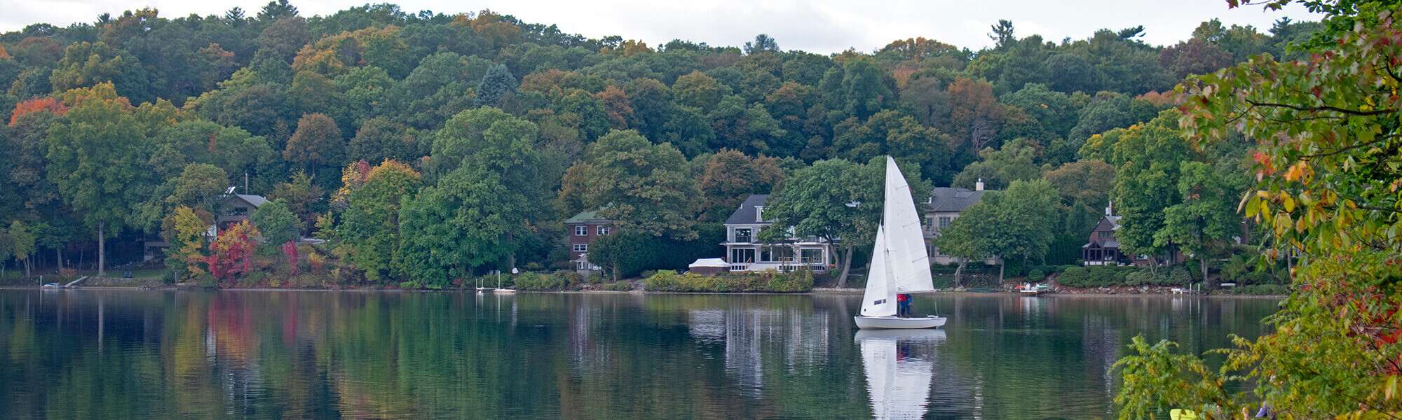 sailboat on lake with houses in background