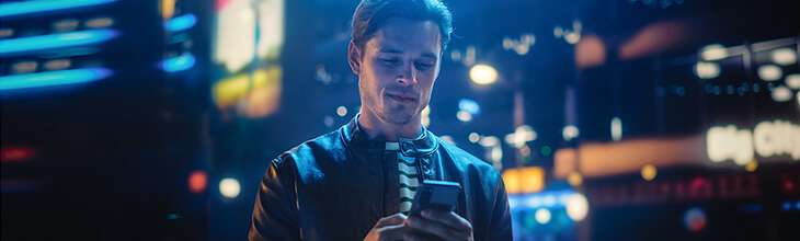 Guy in city nighttime setting uses mobile phone