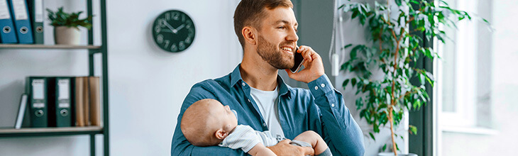 Dad talks on mobile phone while holding baby