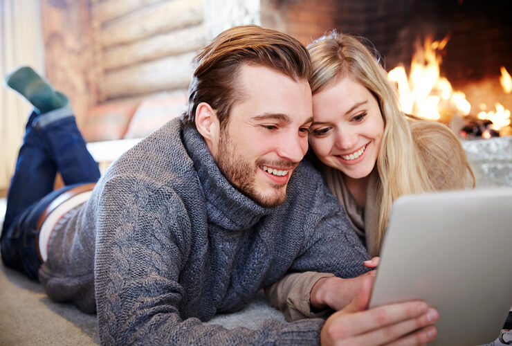 cozy couple watching streaming shows in front of crackling fireplace in the winter